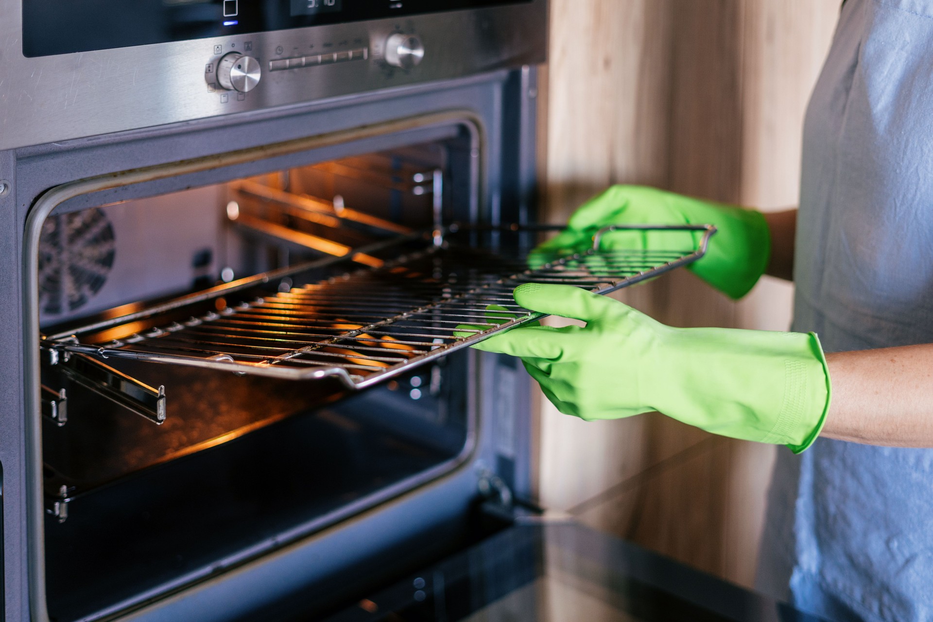 Woman cleaning modern oven in a stylish kitchen with electric appliances